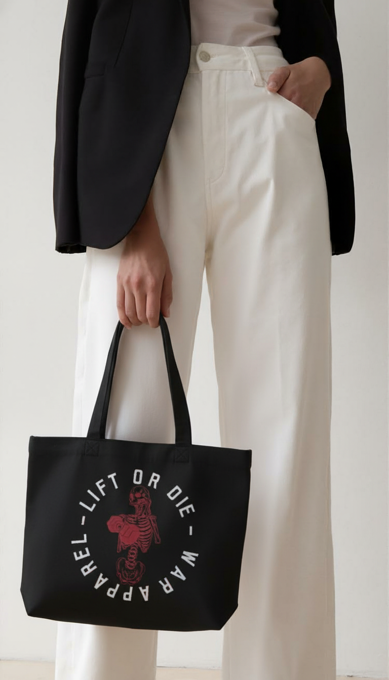 Person holding a black tote bag with WAR APPAREL text  ans red skeleton  and white text against a plain background